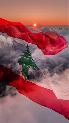 two flags flying in the sky with clouds below