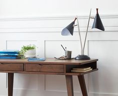 a wooden desk with two lamps on top of it