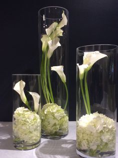 three clear vases with white flowers in them