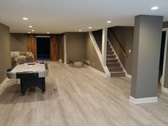 a living room with hard wood flooring and white piano in the center, stairs leading up to the second floor