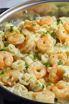 a silver bowl filled with pasta and shrimp