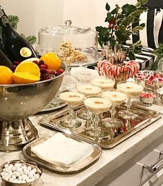 an assortment of desserts and champagne on a buffet table with holiday decorations in the background