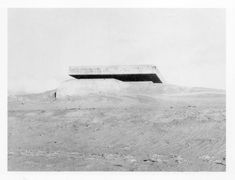 an old black and white photo of a building on top of a hill in the desert