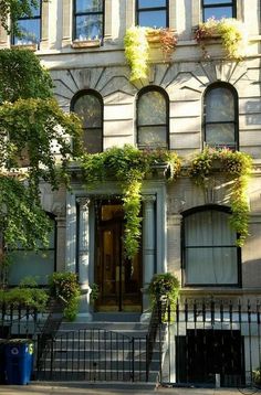 a large white building with lots of windows and plants on the side of it's front door