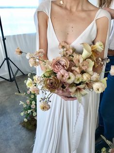 a woman in a white dress holding a bouquet of flowers