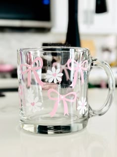 a clear glass mug with pink bows on it