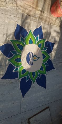 a person standing next to a blue and green flower design on the ground in front of a red fire hydrant