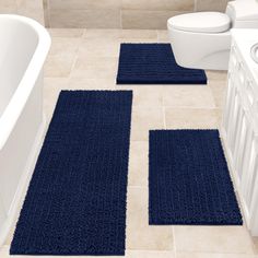 two blue rugs on the floor in a bathroom next to a bathtub and toilet