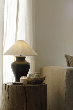 a lamp sitting on top of a wooden table next to a couch in a living room