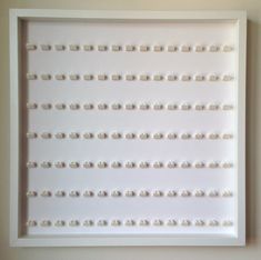 a white framed art piece with lots of small beads on it's sides, hanging on the wall