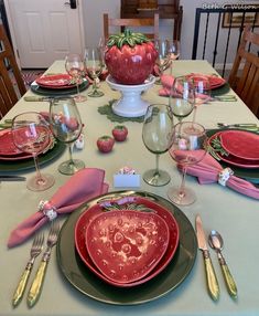 the table is set with plates, silverware and strawberries on top of it