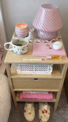 a night stand with books, cups and candles on it