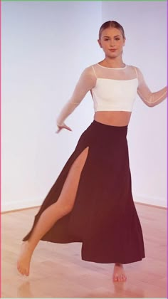 a woman in a black and white dress is dancing with her legs spread wide out