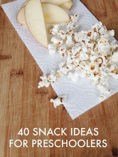 an apple and some popcorn on top of a wooden table with the words 40 snack ideas for preschoolers