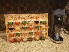 a wooden sign with cups on it next to a coffee maker