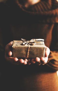 a person holding a wrapped present in their hands