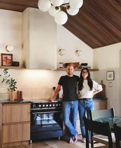 a man and woman standing next to each other in front of a stove top oven