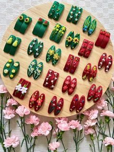 a wooden platter filled with lots of different types of decorated nail polish on top of pink flowers