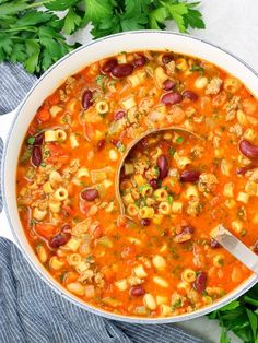 a large pot filled with soup on top of a blue towel next to parsley