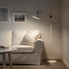 a living room with a white couch and lamp on the wall next to a coffee table