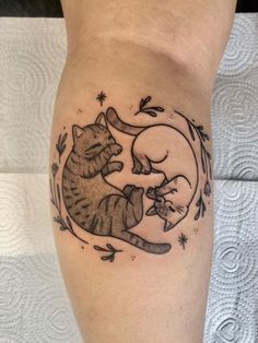 a woman's leg with a cat and mouse tattoo on it, which is sitting next to another cat