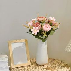 a vase filled with pink flowers sitting on top of a table next to a mirror