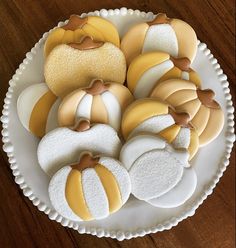 a white plate topped with cut out pumpkins on top of a wooden table next to cookies