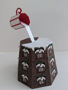 an origami christmas tree box with numbers on it and a red hat sticking out of the top