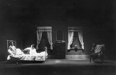 black and white photograph of two women in bed with drapes on the windows behind them