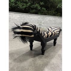 a zebra print bench sitting on top of cement floor next to a brick wall with trees in the background