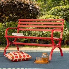 a red bench sitting on top of a sidewalk next to a pillow