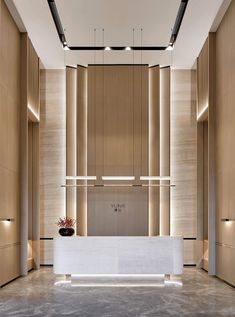 an empty lobby with a white reception table and lights on the wall, along with wooden paneling