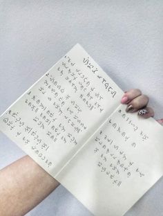 a woman's hand holding up a piece of paper that has writing on it