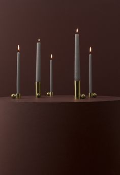 five candles are lined up in a row with one candle on the other side and three lit