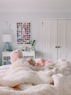 there is a teddy bear that is laying on the bed with pink blankets and pillows