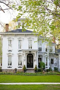 a large white house sitting on top of a lush green field