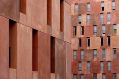 the side of a building with many windows and one bird perched on it's perch