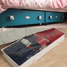 a bed sitting next to a blue suitcase on the floor