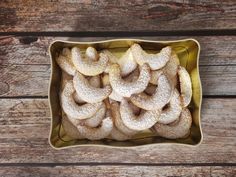 powdered sugar coated cookies in a yellow dish on a wooden table, top view