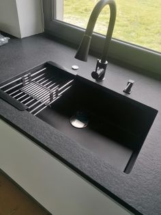 a black sink sitting on top of a counter next to a window