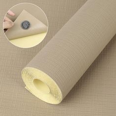 a roll of beige colored fabric with a hand holding it up to the side and an adhesive sticker on top