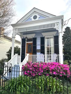 a white house with black shutters and pink flowers