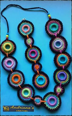 multicolored beaded necklaces with beads on a blue background, one is made from yarn and the other is crocheted