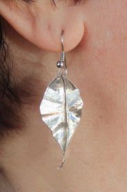 a close up of a person's ear with a leaf shaped earrings on it