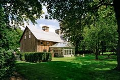 a large wooden barn surrounded by lush green trees