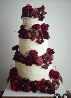 a three tiered cake with berries and flowers on top