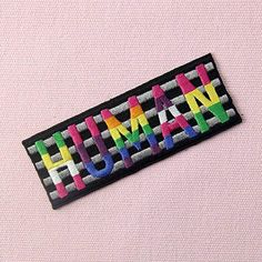 a patch with the word human written in multicolored letters on it's side