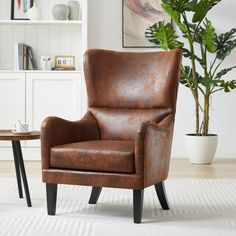 a brown leather chair sitting on top of a white rug next to a potted plant