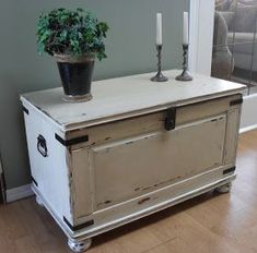 an old chest with two candles and a potted plant on top