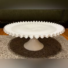 a white cake plate sitting on top of a carpeted floor next to a couch